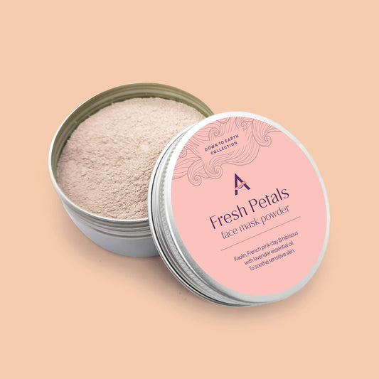 A round tin container with a pink label on the lid, displaying the product name 'Fresh Petals face mask powder'. The container is open, showing the light pink powdered product inside.