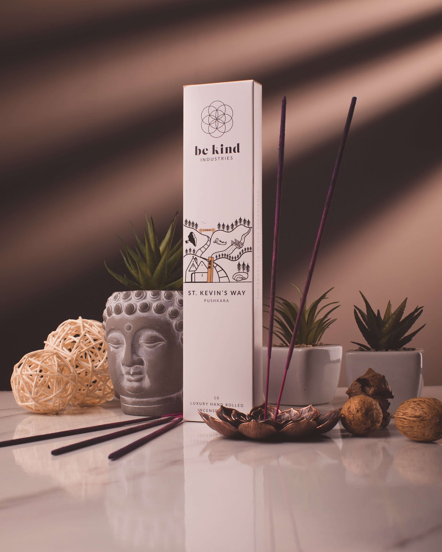 A package of Be Kind brand incense sticks, labeled 'St Kevin's Way' sitting on a marble table with plants and other decor