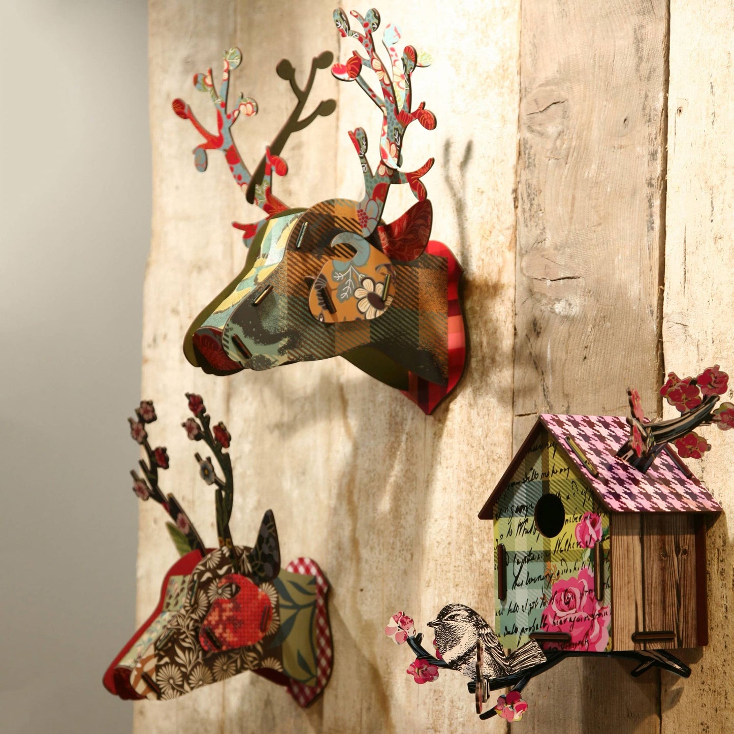 Decorative wall art with deer heads and a birdhouse on a wooden background