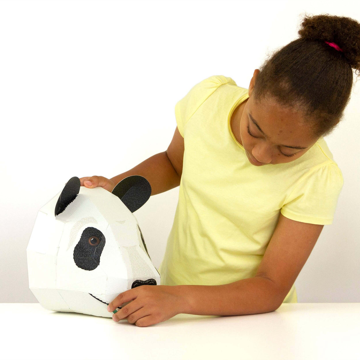 Child playing with a panda-shaped pillow on a white background