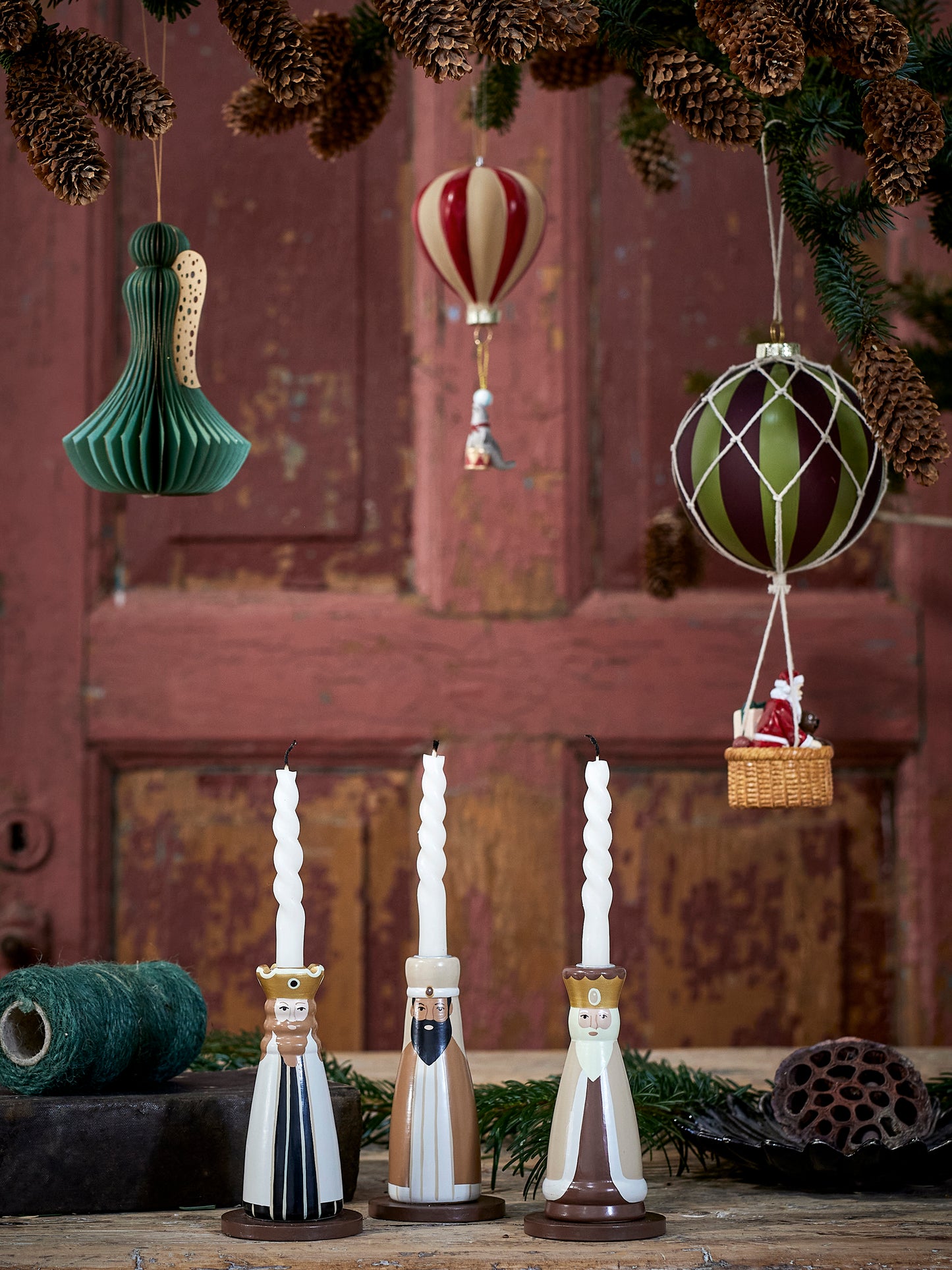 Three wise men painted candle holders with taper candles. Sitting on a table in Christmas scene