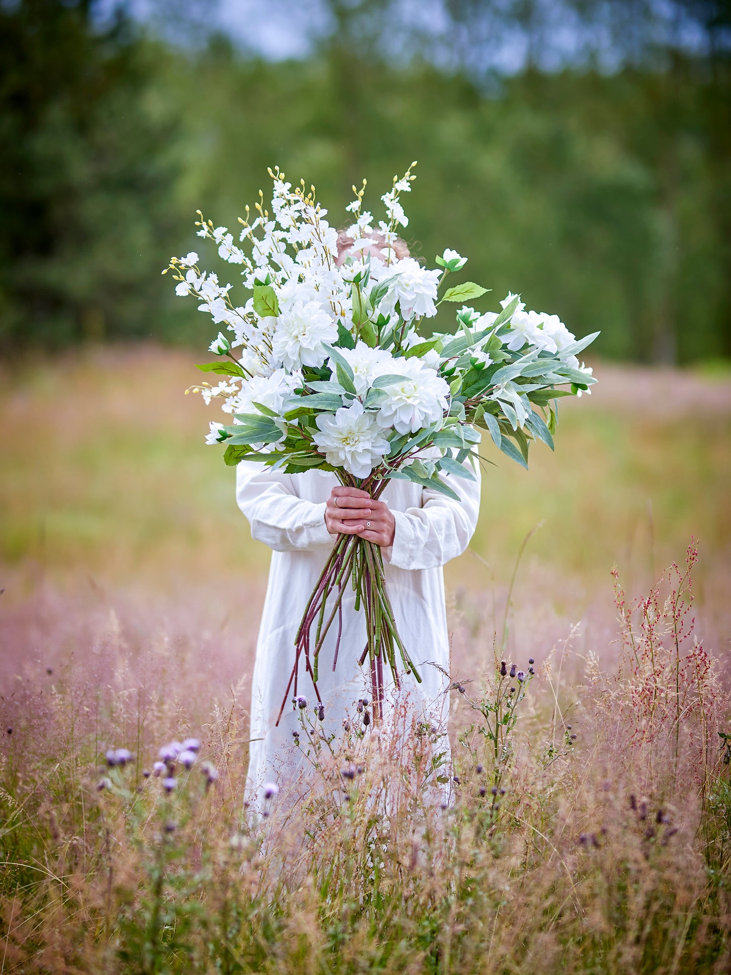 Person holding a bouquet of white flowers in a field