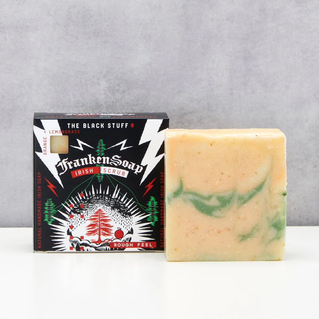 Bar of soap with green swirls next to its packaging on a gray background