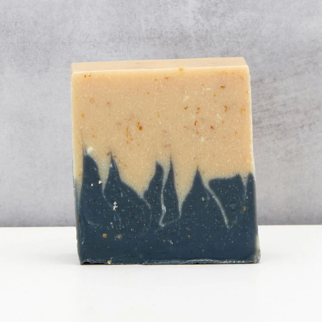 Two-tone soap bar with beige top and dark blue bottom on a gray background