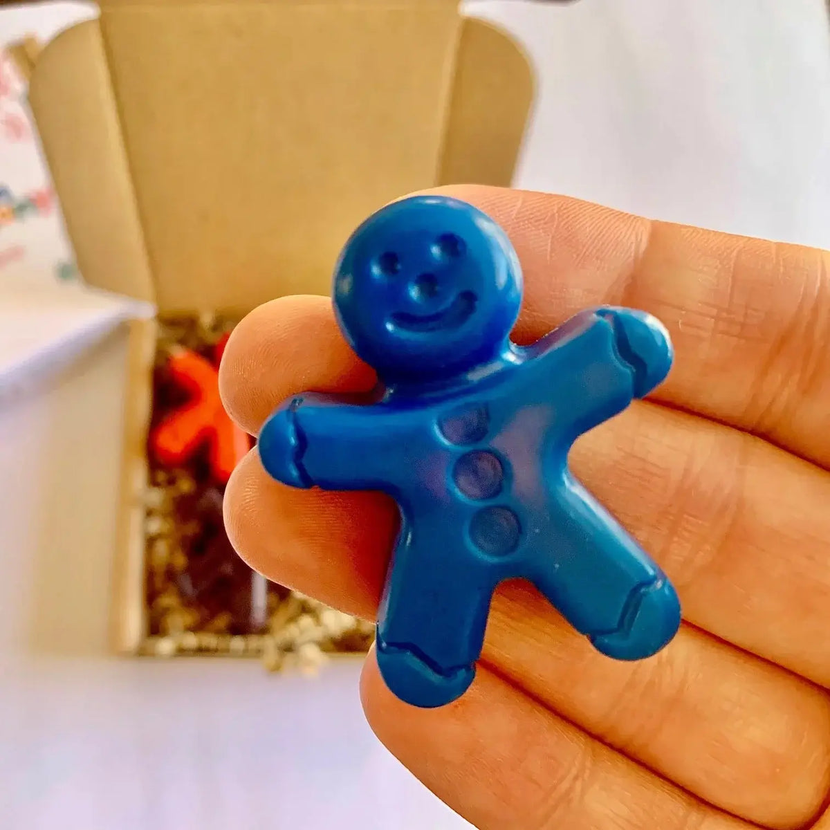 Blue gingerbread man crayon held in a hand with a blurred background