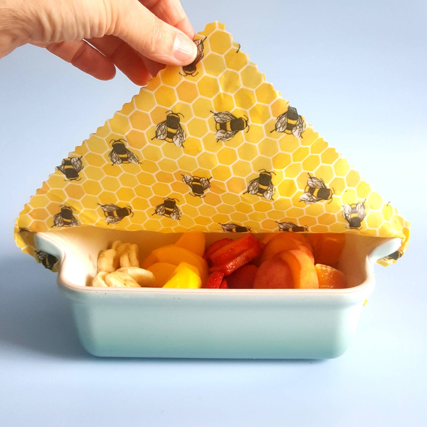 Showing how a bowl of leftovers can be covered with a wax food wrap