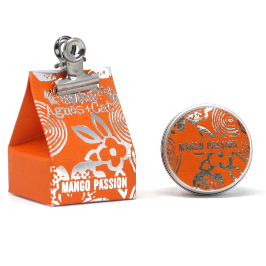 A container of Agnes and Cat Mango Passion Fruit lip balm beside its packaging against a white background