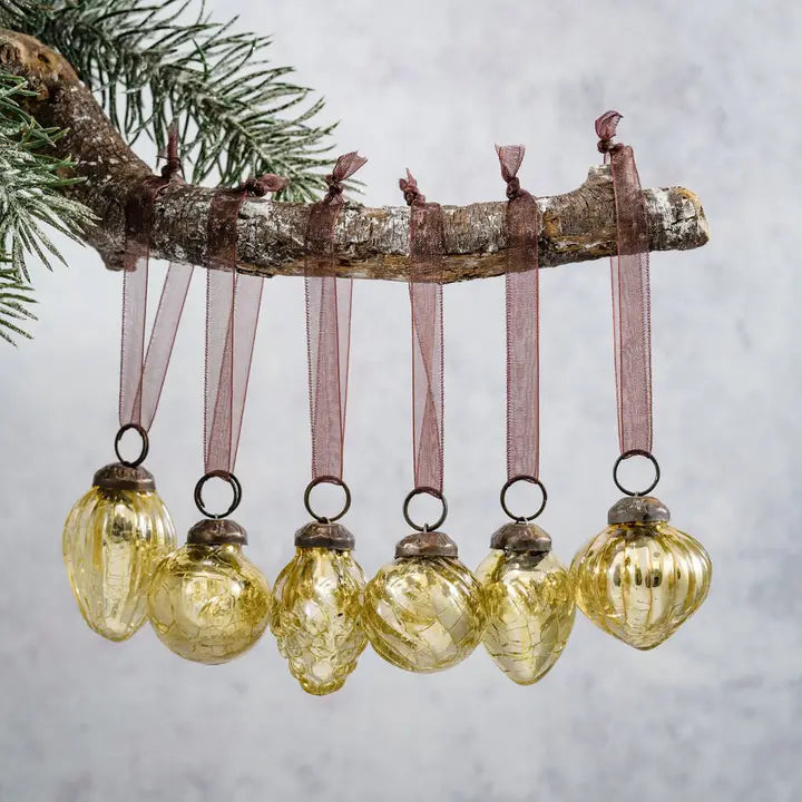 Decorative Christmas ornament with glass balls and ribbons hanging from a branch against a neutral background