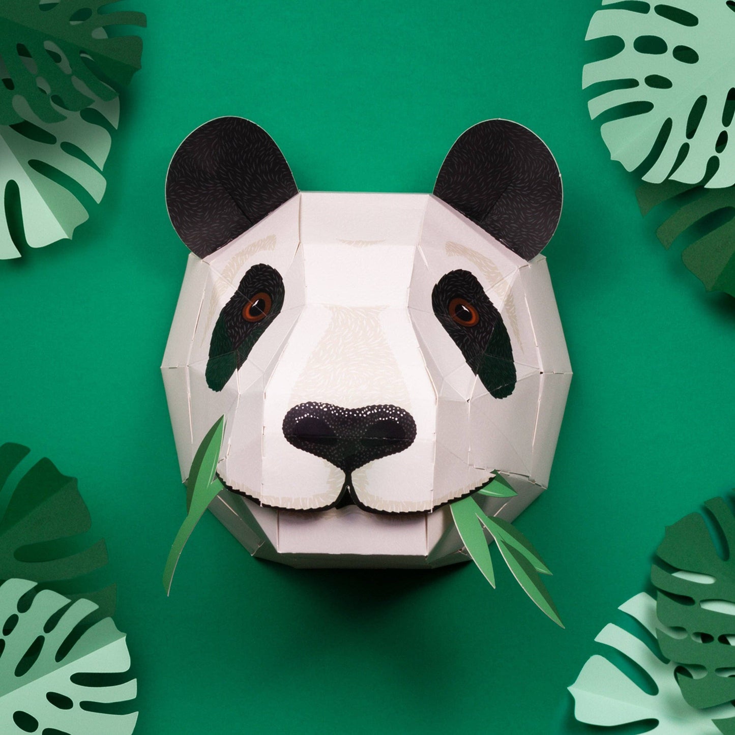 Panda head sculpture on a green background with leaf patterns