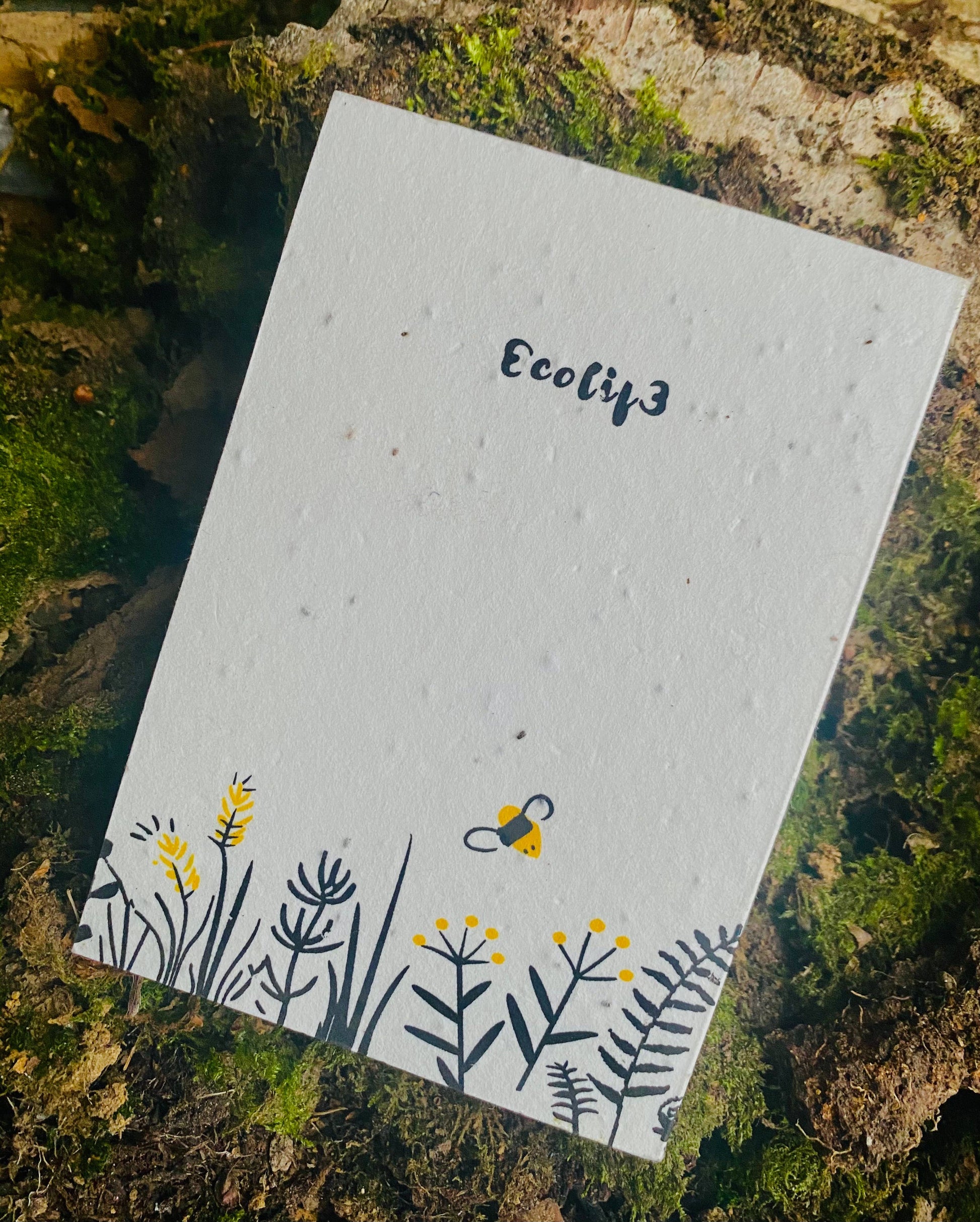 A white A6 notepad with a plantable design featuring black and yellow bee illustrations, labeled 'Ecolif£'