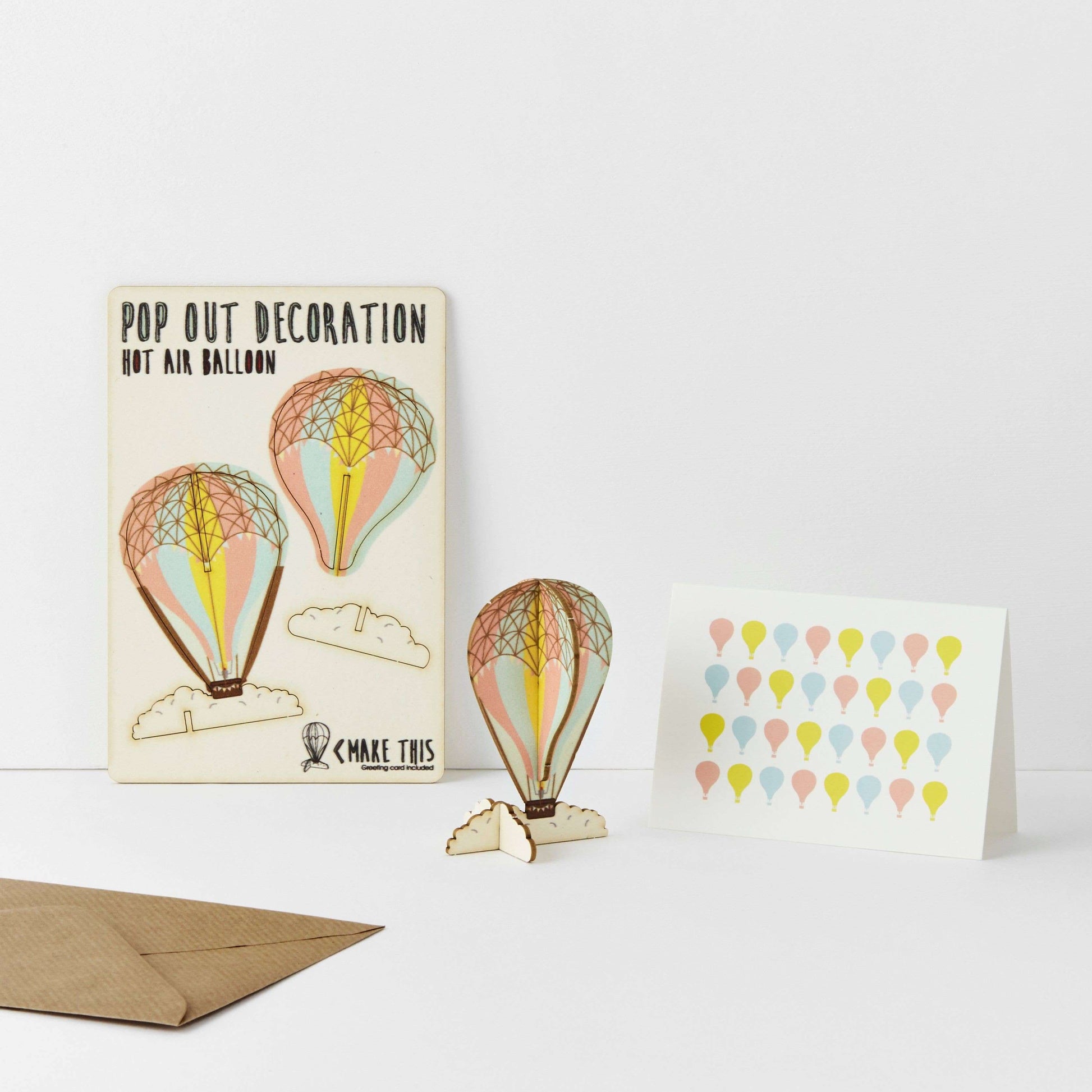 A greeting card with a pop-out hot air balloon design, accompanied by an A7 greeting card with a repeat hot air balloon pattern and a brown A6 envelope.