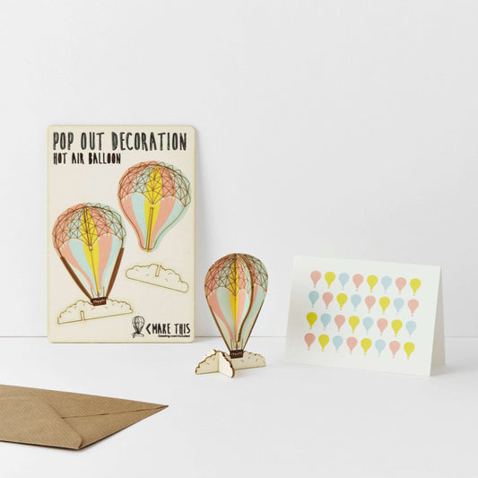 A greeting card with a pop-out hot air balloon design, accompanied by an A7 greeting card with a repeat hot air balloon pattern and a brown A6 envelope.