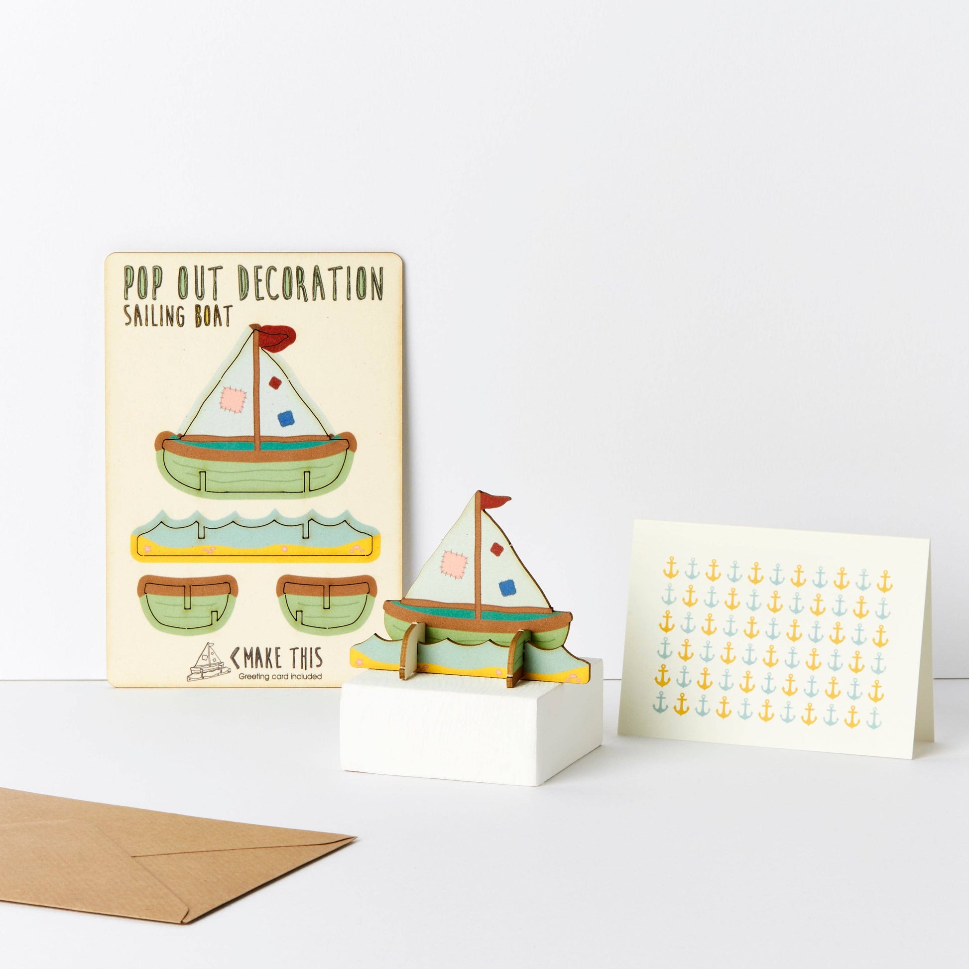 A greeting card with a pop-out sailing boat decoration and an envelope, showcasing a cartoon-style sailboat and anchor patterns.