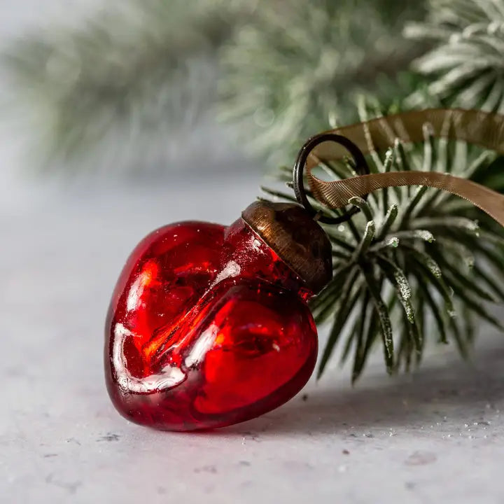 Red glass ornament on a branch with a blurred green background