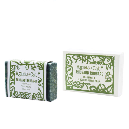 A bar of coconut butter soap with 'Rhubarb Rhubarb' embossed on the top, next to its packaging box with a floral design.