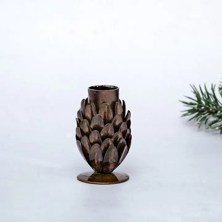 Decorative bronze small pine cone shaped candle holder on a white background
