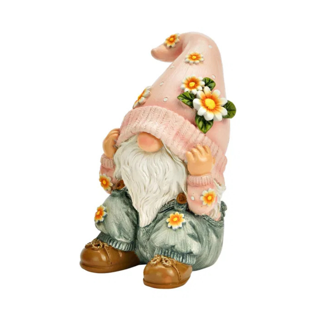 Gonk figurine with a pink hat and flower decorations on a white background