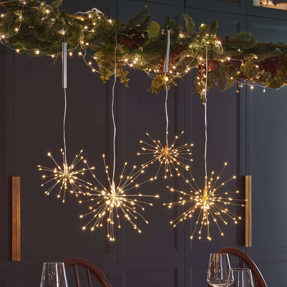 Decorative table setting with string lights shaped like fireworks and a garland above.