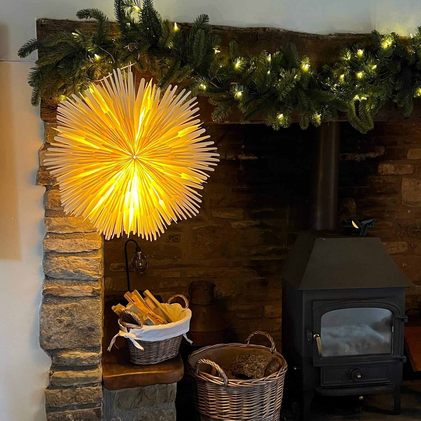 Sunburst decoration lit up and hanging on a mantlepiece decorated for Christmas