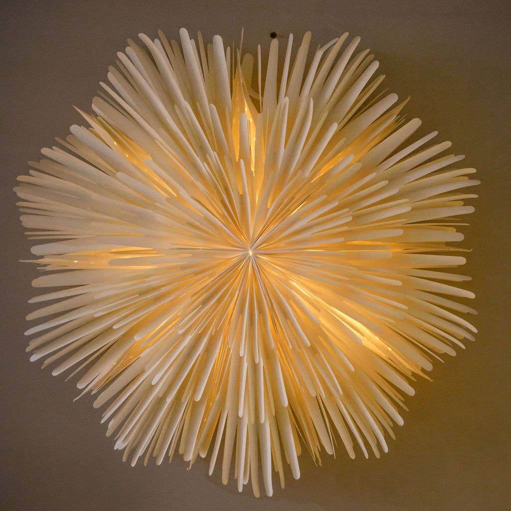 A large white paper wall decoration in a sunburst shape, with visible hanging cords.