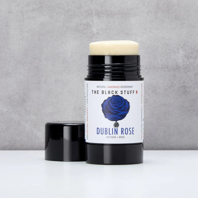 Deodorant stick with 'Dublin Rose' label on a gray background opened with lid sitting beside it.
