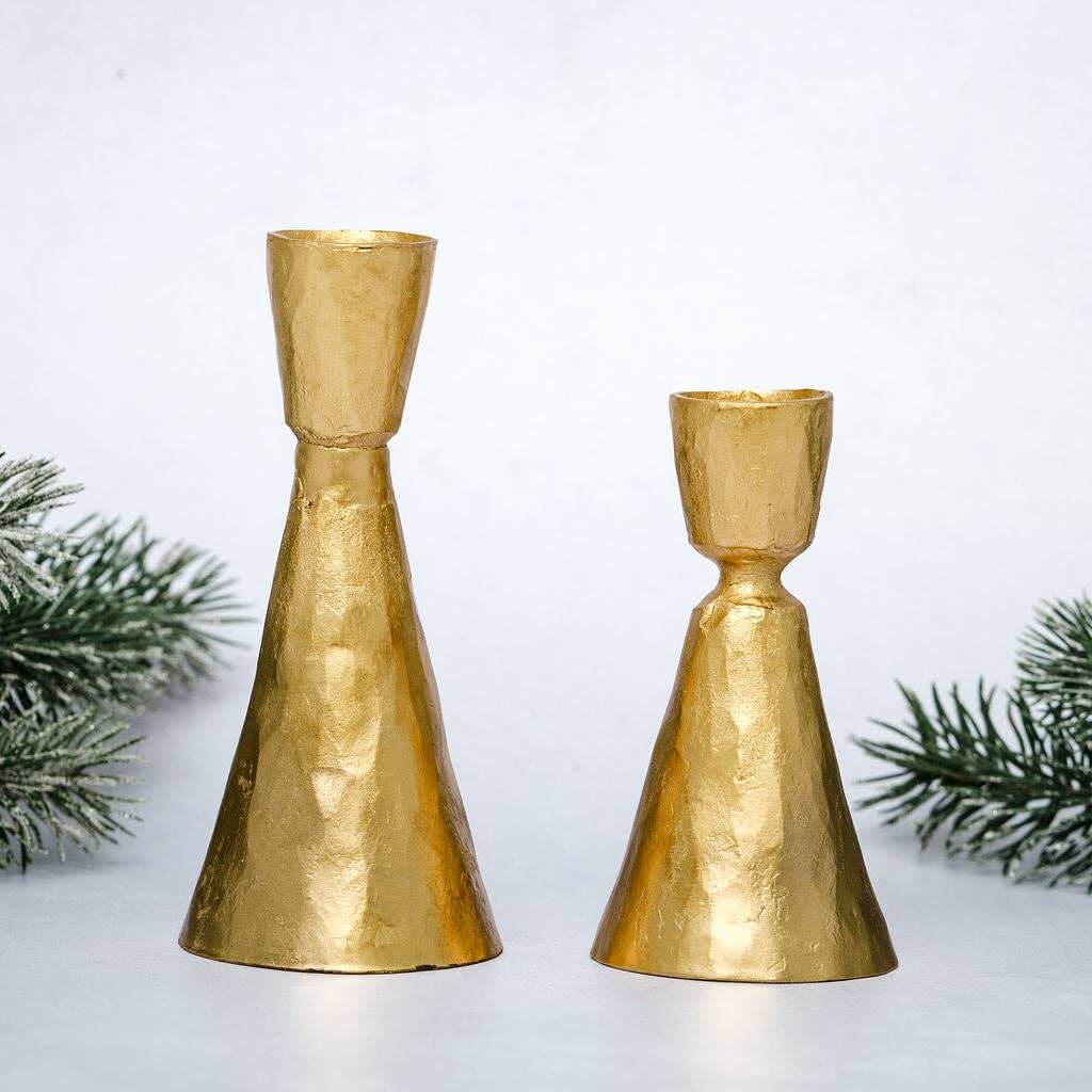 Two gold coloured candle sticks on festive background