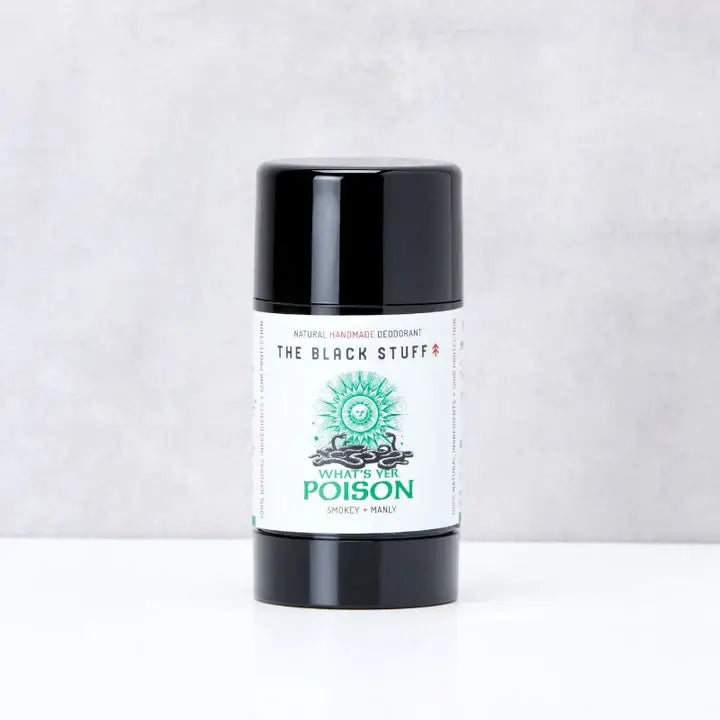 A closed black deodorant stick labeled 'The Black Stuff - What's yer Poison', presented on a neutral background.