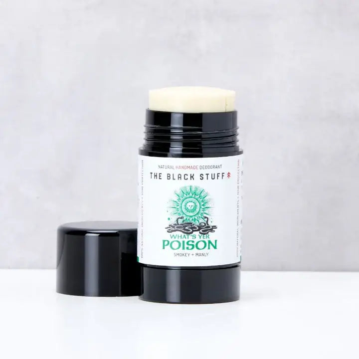 An open black deodorant stick labeled 'The Black Stuff - What's yer Poison', presented on a neutral background.