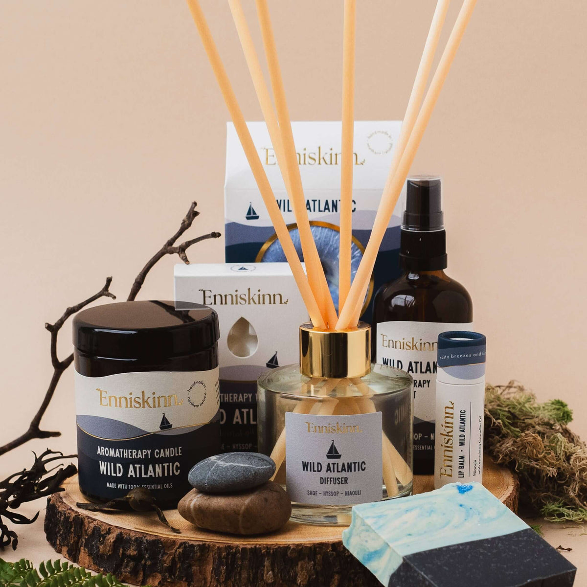 Collection of Enniskinn wellness products including candles, diffusers, and soap on a wooden surface.