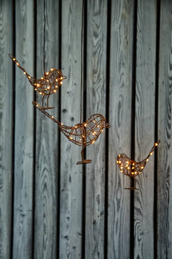 Decorative metal birds with string lights on a wooden background