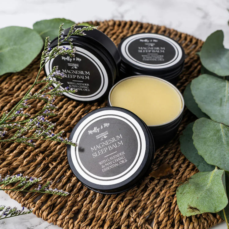 Magnesium sleep Balm from Molly and Me on a woven mat and eucaplyptus leaves