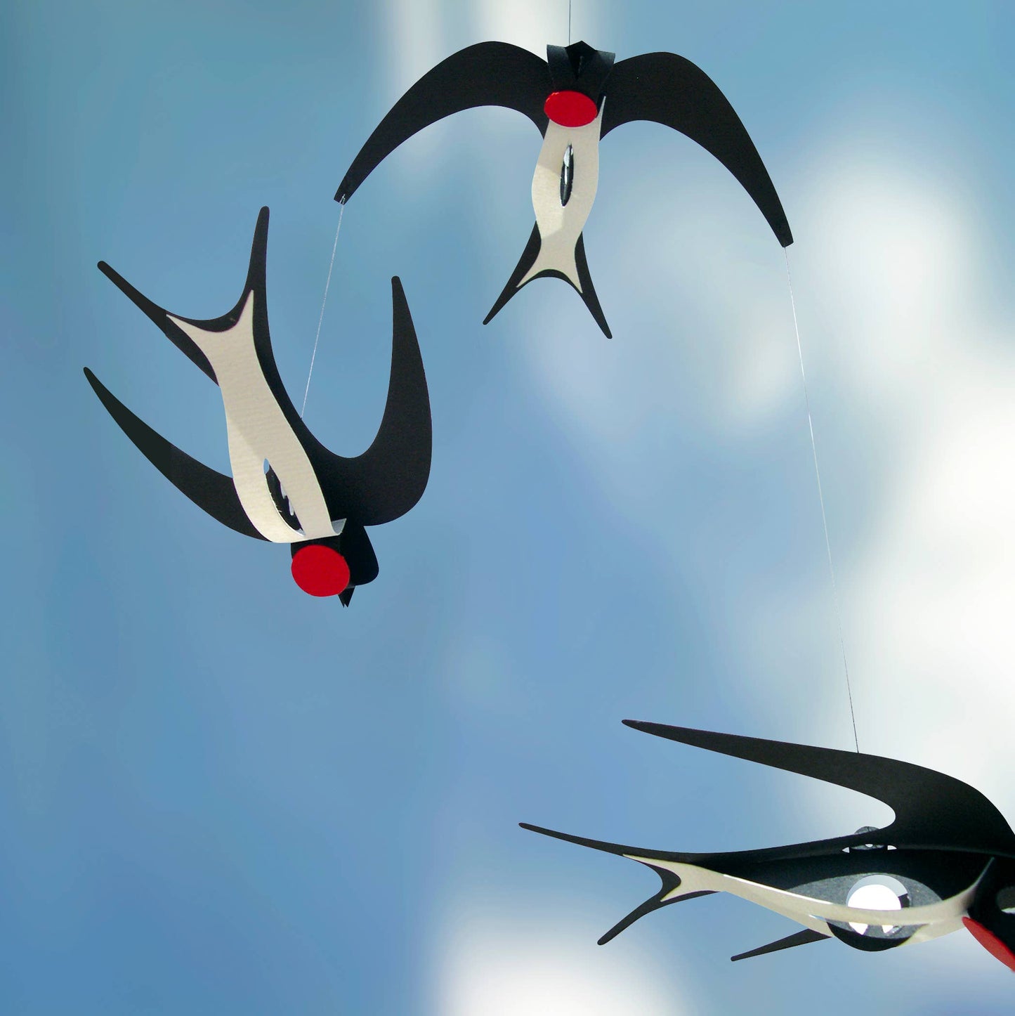 Paper swallow mobile against a blue sky