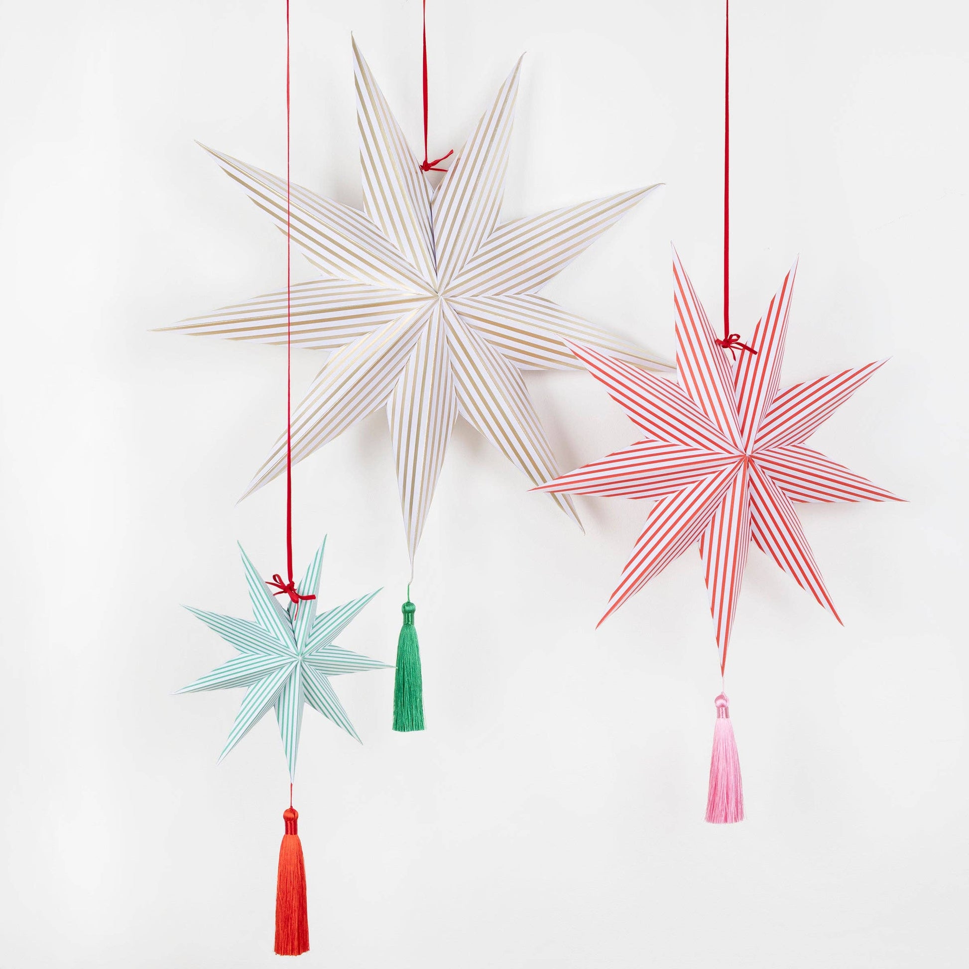 Decorative star-shaped hanging ornaments with tassels on a white background