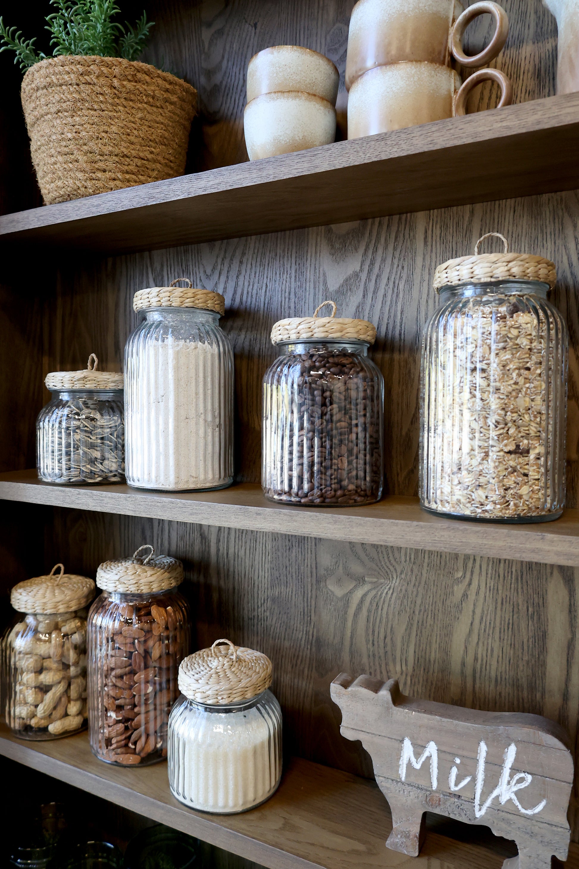 Ribbed glass storage jar with wicker lid on a dresser