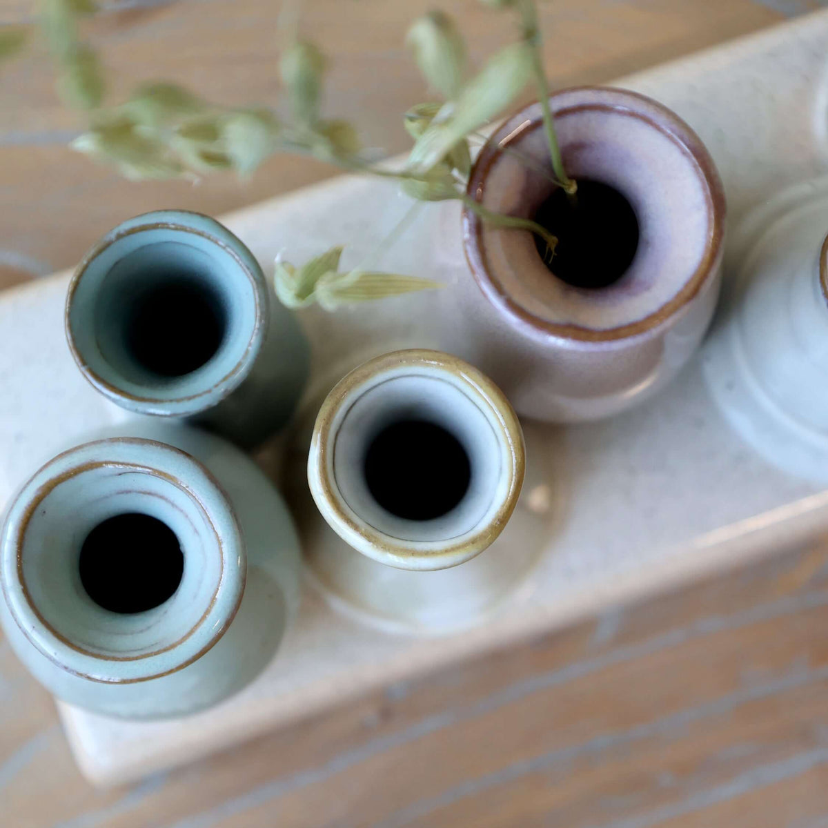 Set of small ceramic vases on a ceramic surface with a seashell in the foreground.