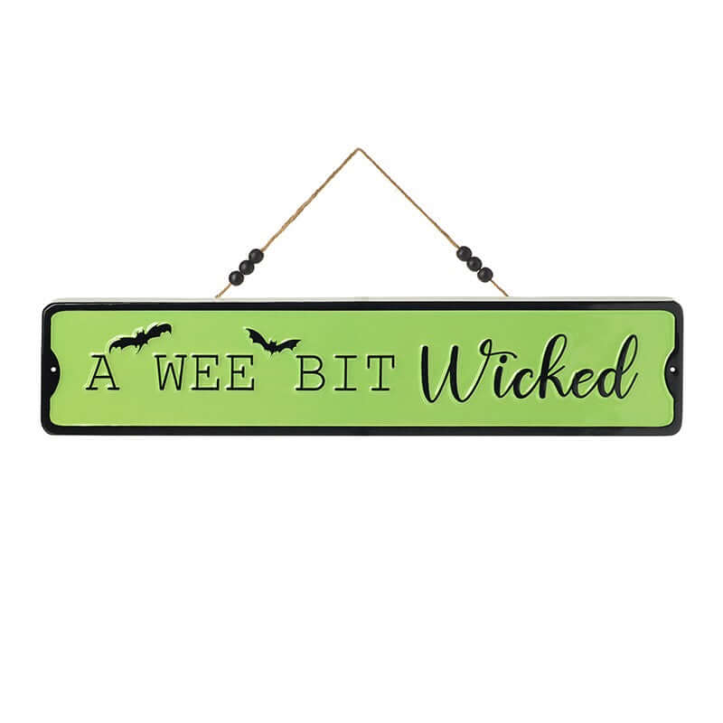 A rectangular Halloween wall sign with a light green background and black border, hanging from a string with black beads. The sign reads 'A WEE BIT Wicked' in black lettering, with two small bat silhouettes on the left side.