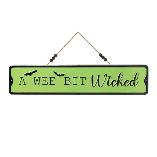 A rectangular Halloween wall sign with a light green background and black border, hanging from a string with black beads. The sign reads 'A WEE BIT Wicked' in black lettering, with two small bat silhouettes on the left side.