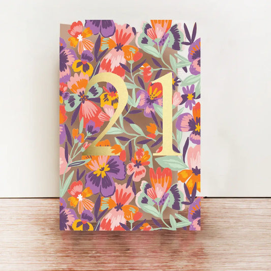 A colorful floral birthday card with the number 21 printed on the front, accompanied by a brown kraft envelope.
