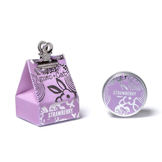 Agnes + Cat tin of lip balm beside cardboard packaging in lavender with silver design and metal clip