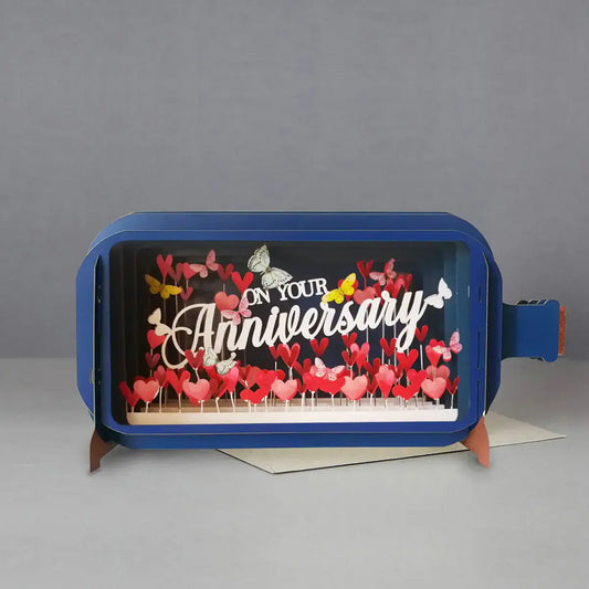 A 3D pop-up greeting card with the message 'On Your Anniversary' displayed inside a bottle design, accompanied by red and pink butterfly cut-outs.