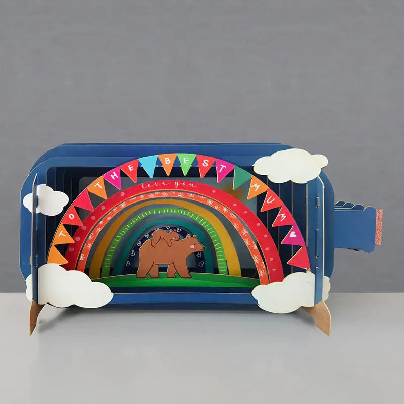 A colorful pop-up greeting card in a bottle with a rainbow, clouds, and a bear design, meant for mothers.