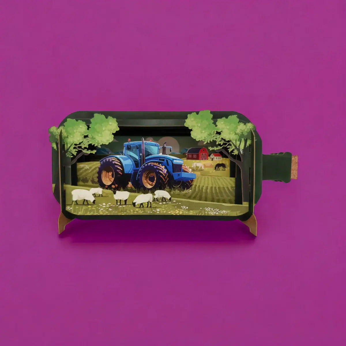 A pop-up greeting card depicting a three-dimensional scene with a blue tractor and sheep in a field, made by Alljoy Design.