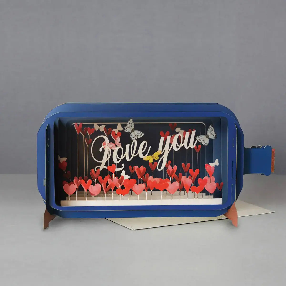 Pop up card with a field of red hearts at the bottom. The words 'Love You' and butterflies and hearts in the background