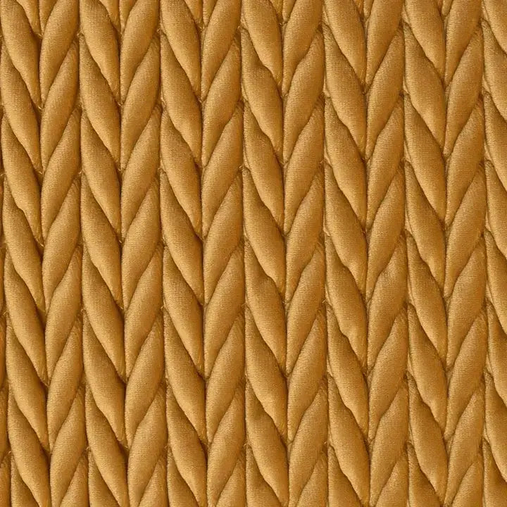 A close-up of a textured woven fabric with a repeating chevron or braided pattern in warm tan and camel tones.