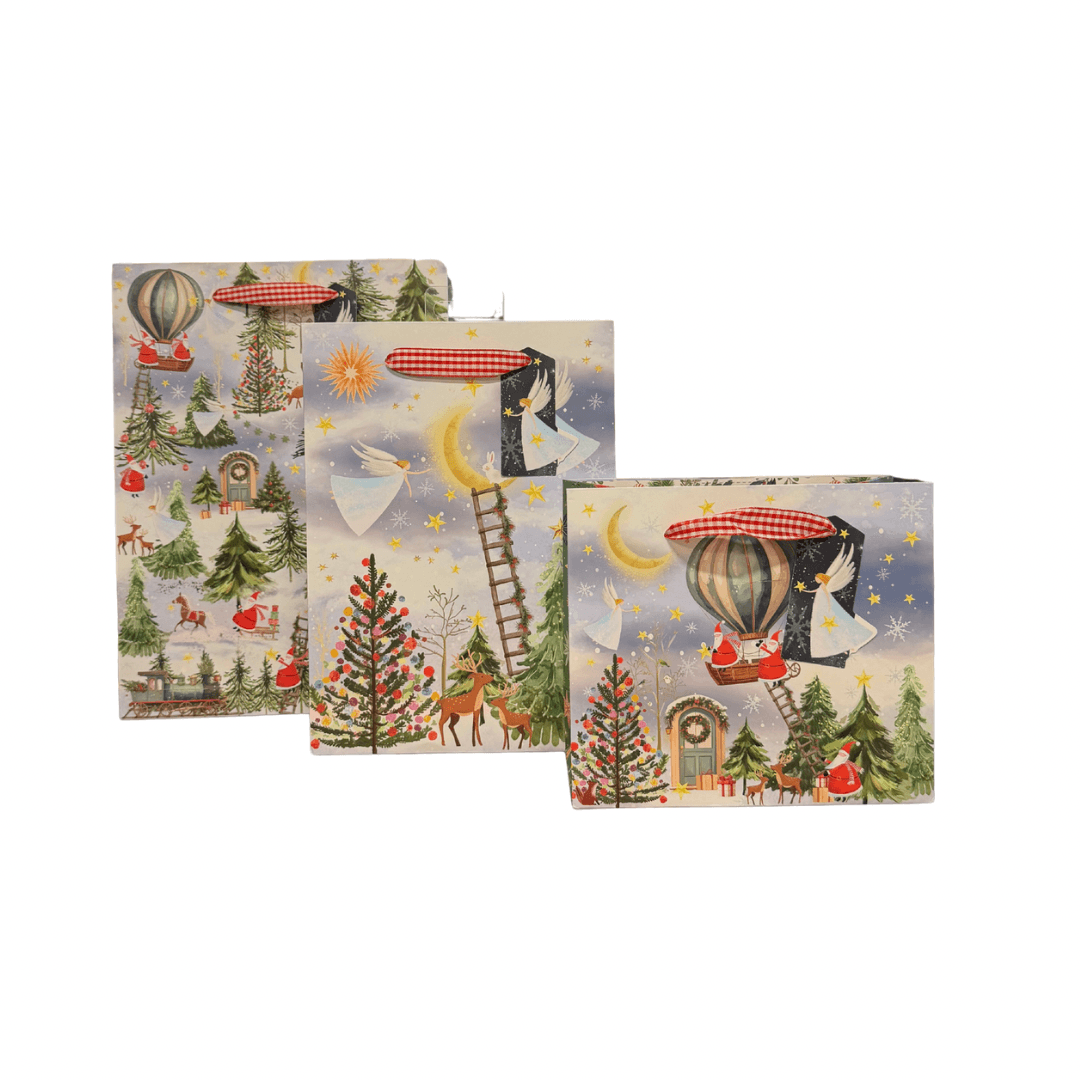 Three square decorative gift bags with whimsical illustrated winter and aerial scenes, including hot air balloons, trees, stars, a ladder, and small figures, shown on a plain white background.