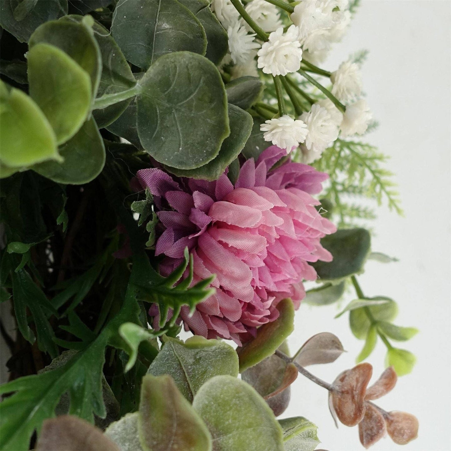Close-up of a bouquet with pink and white flowers and green leaves on a light background