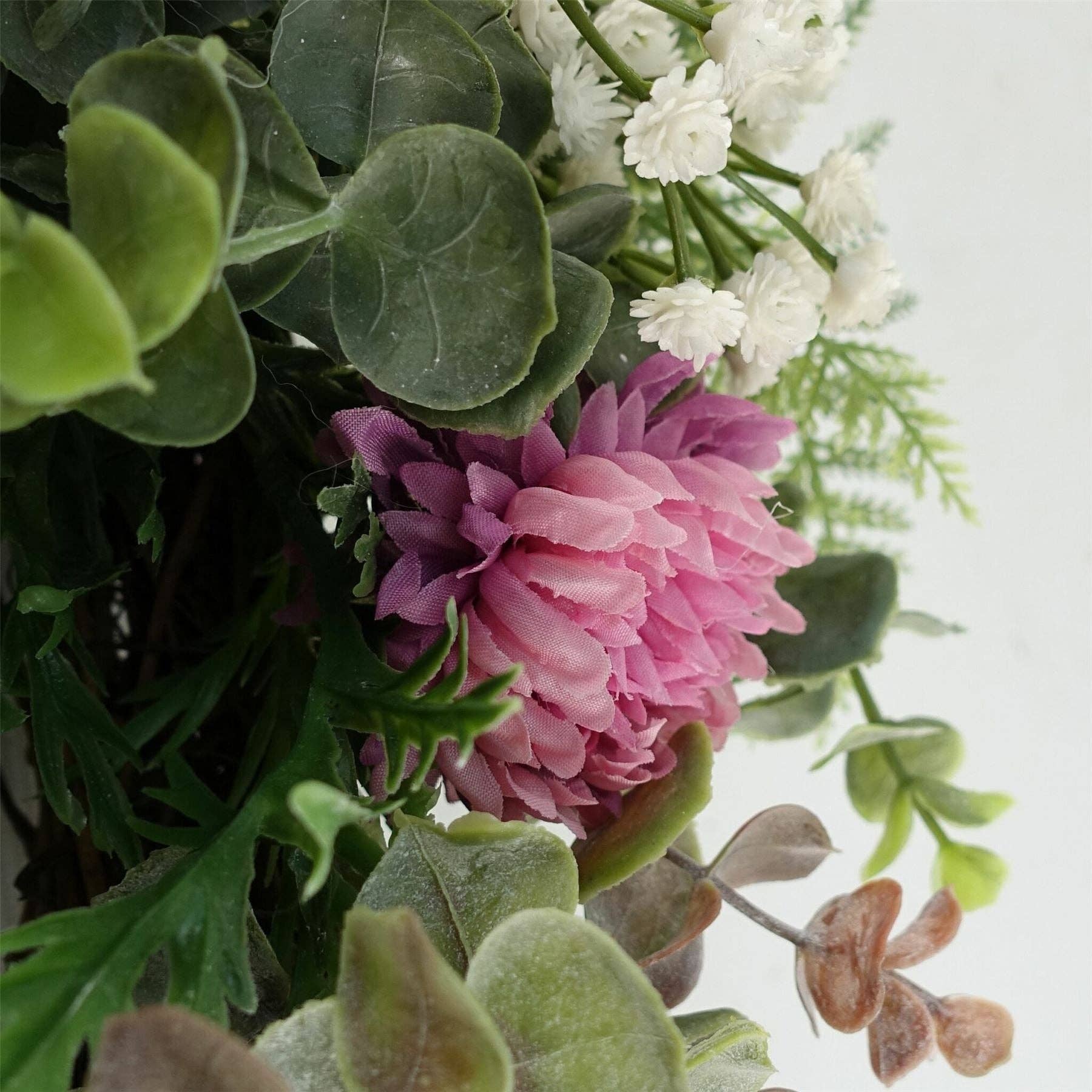 Close-up of a bouquet with pink and white flowers and green leaves on a light background