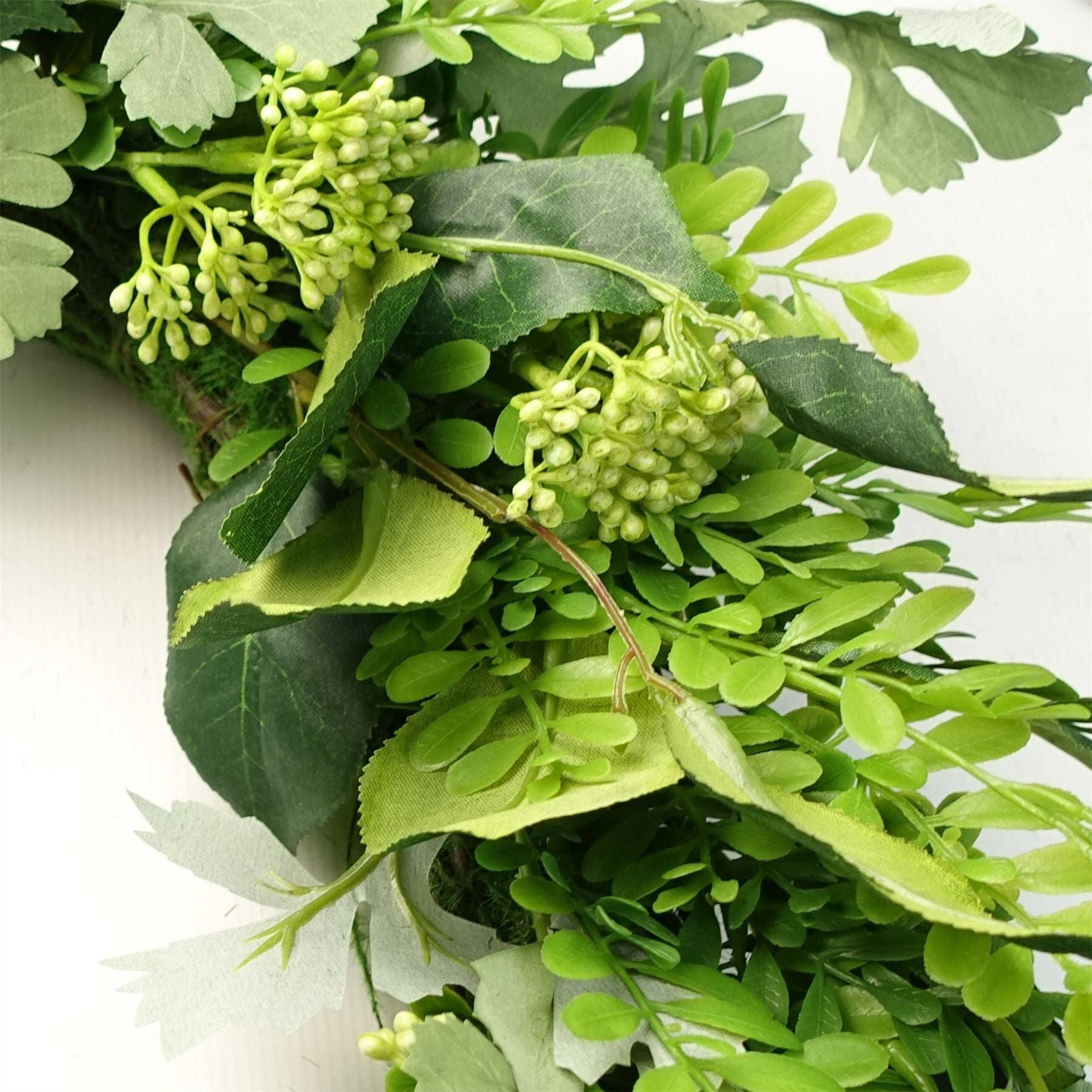 Close-up of green artificial leaves and flowers on a white background