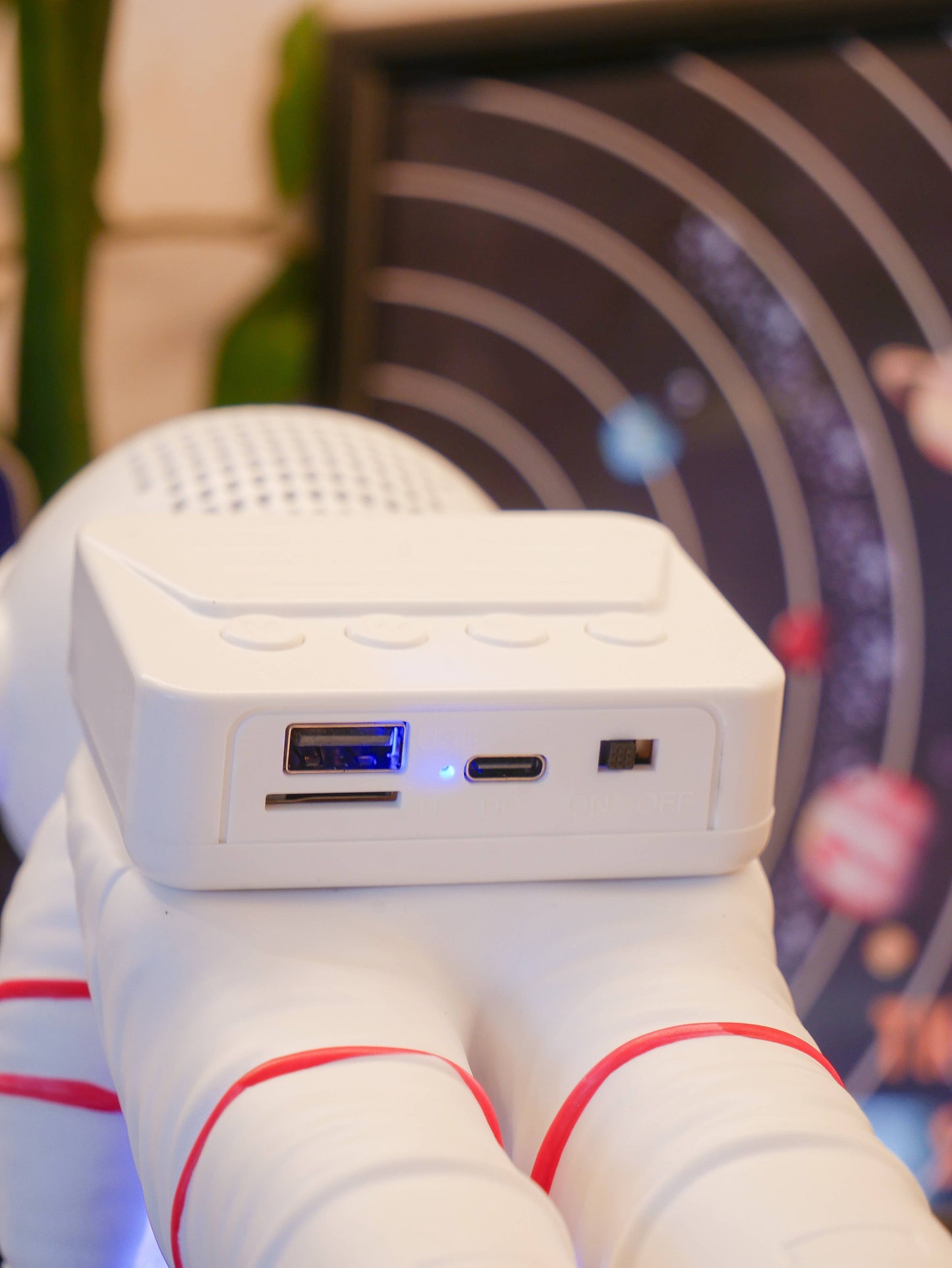 White electronic device with USB and micro USB ports held by a white glove with red accents.
