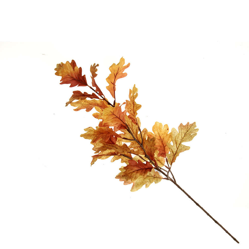 An artificial autumn oak leaf branch with leaves in shades of orange, yellow, and brown on a solid white background.